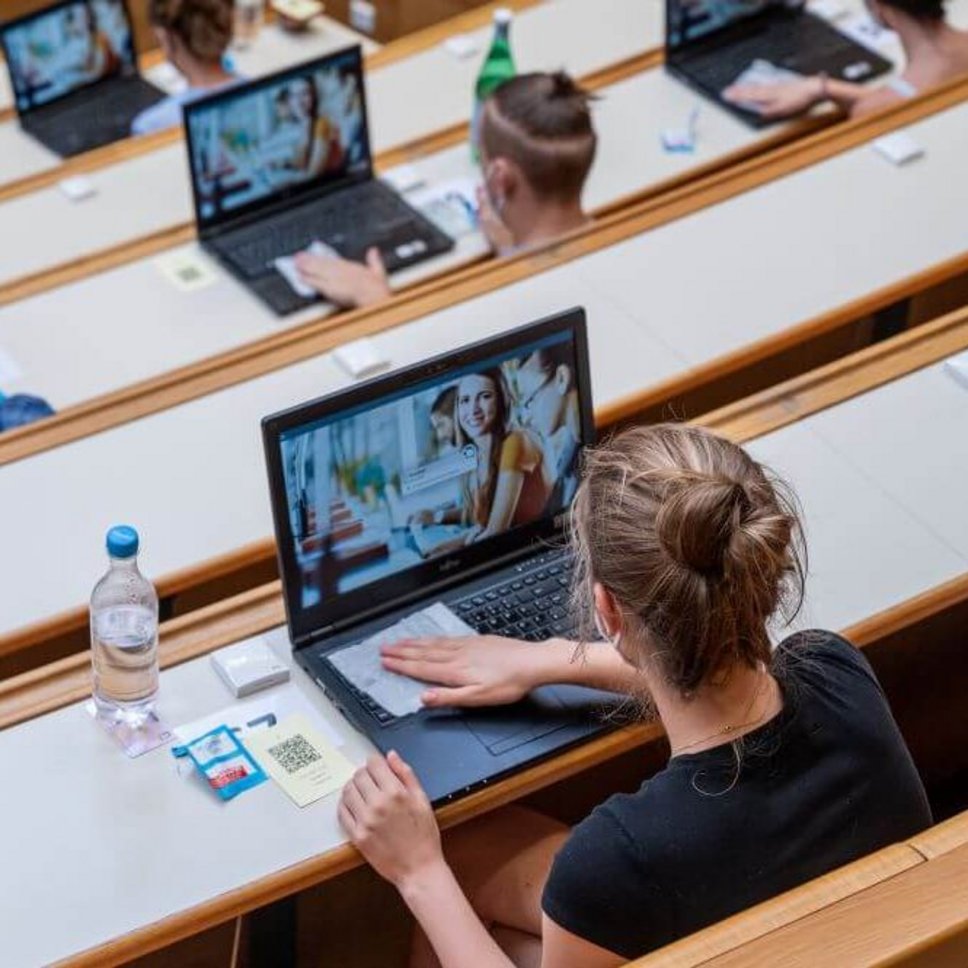 Studierende im Hörsaal vor Laptop