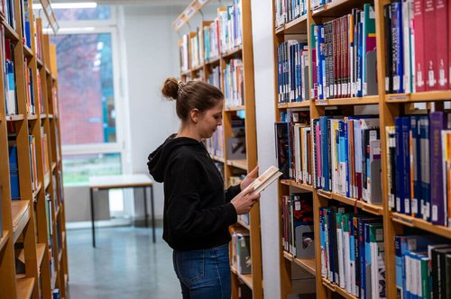 Frau vor Bücherregal in Universitätsbibliothek